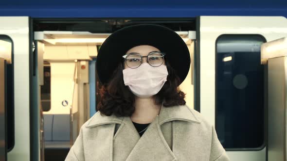 Portrait of an Attractive Young Woman in a Protective Medical Suit Standing Alone at an Empty Metro alt