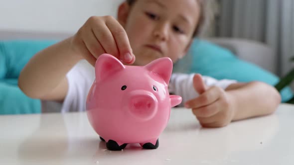 Little Girl Saves Money with a Piggy Bank at Home