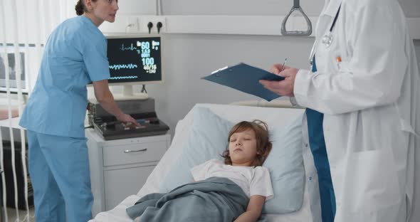 Senior Doctor and Nurse Checking Sick Child Patient Sleeping in Hospital Bed alt