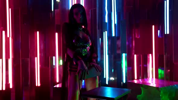 Passionate Young Woman Posing on the Background Wall with Colorful Neon Lights on the Stage Near the alt