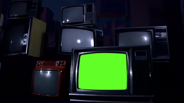 Retro TV Set turning On Green Screen Among Many Vintage Televisions. Dolly Shot. 4K Version. alt