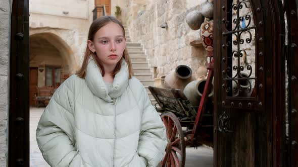 Thoughtful Young Girl Standing in Doorway in Old Town alt
