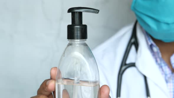 Doctor in Face Mask Holding Hand Sanitizer Gel, Close Up alt