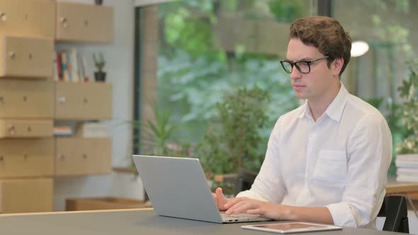 Young Man Working on Laptop in Modern Office alt
