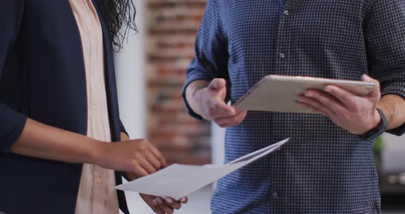 Mid section of man and woman shaking hands at office alt