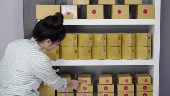 young woman entrepreneur counting parcel boxes in her own job shopping online business at home