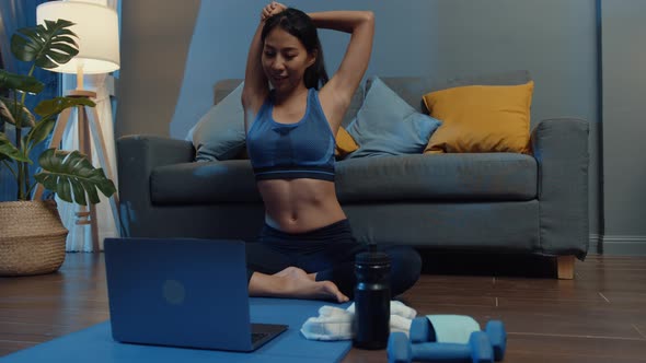 sia lady in sportswear exercises doing work out and using laptop to watch yoga video tutorial.