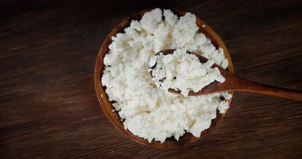 The Cottage Cheese Rotates in a Wooden Plate and Spoon.