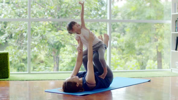 Little girl and young mother doing exercise on fitness mat