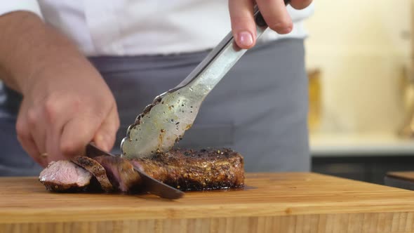 Male puts pieces of grilled meat on Board decorated with grilled vegetables alt
