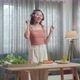 Woman With Healthy Food Listening To Music With Headphones And Dancing While Slicing Cucumber - VideoHive Item for Sale