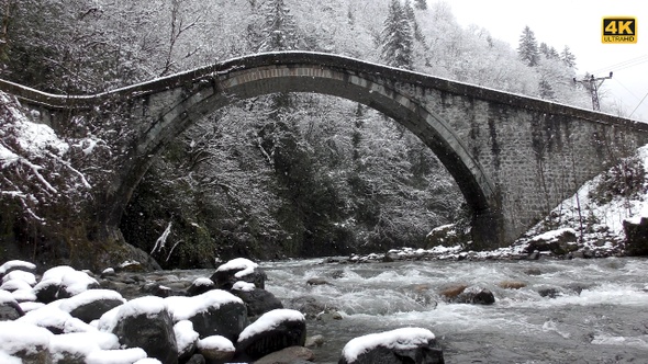 Historical Arch Bridge With Stream and Snow