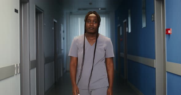 A Female Doctor Walks Along an Empty Corridor of the Hospital alt
