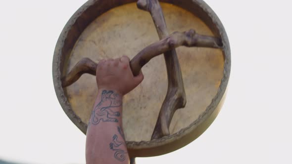 Fat Man with Tattoos on Arm Raises Up Shamanic Drum alt