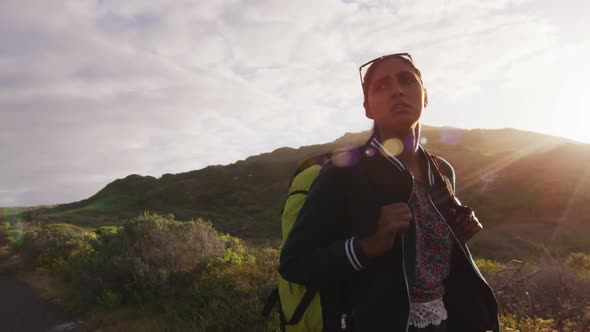 Mixed race woman walking on road hitchhiking on sunny day alt