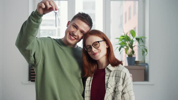 Man Shakes the Keys to the Apartment in His Hands a Woman with Glasses Stands Nearby