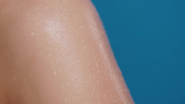 Water Drops Falling Down on Woman Arm with Camera Movement on Blue Background alt