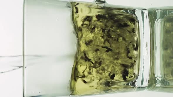 Vertical Video Black Tea Particles Pouring Into Glass Transparent Mug and Filled with Boiling Water