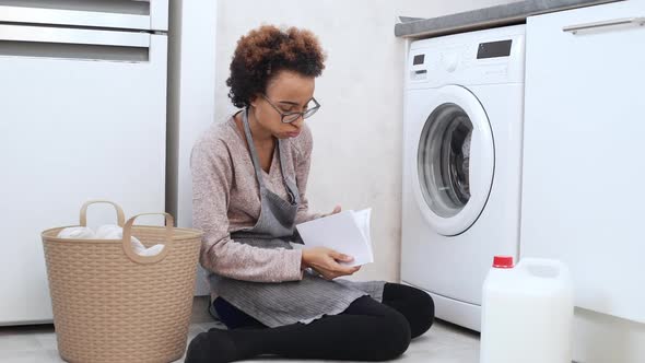 Young Vexed African American Female in Glasses Sitting on Floor and Trying to Sort Out How to Use alt