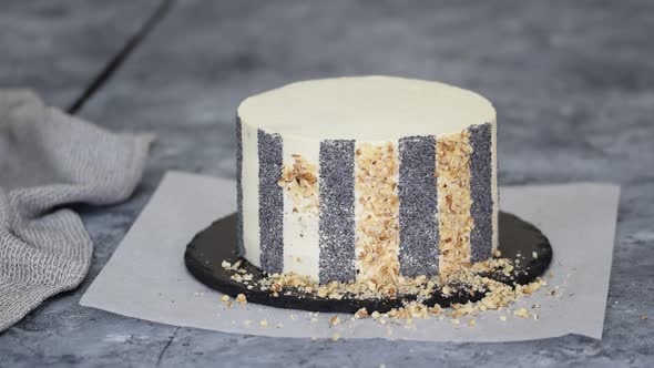 Unrecognizable Woman Pastry Chef Decorating Cake with Walnut and Poppy Seeds