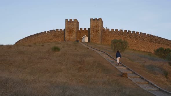 Woman going up on the stairs to Arraiolos castle at sunset in Alentejo, Portugal alt