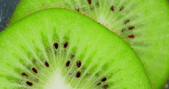 Cut Into Slices of Ripe Kiwi Under Water with Air Bubbles