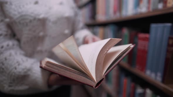  Unrecognizable Woman Turns Over the Pages of Old Paper Book in Library alt