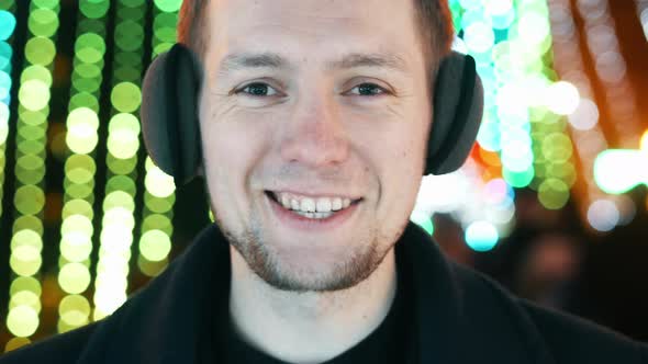 Young Happy Man Portrait with Warm Headphones Smiling and Looking at Camera, Bokeh of Christmas alt