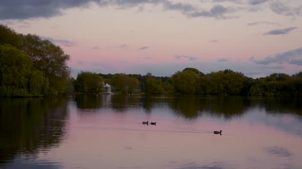 Sunsets over a lake while a lone fisherman casts his line. alt