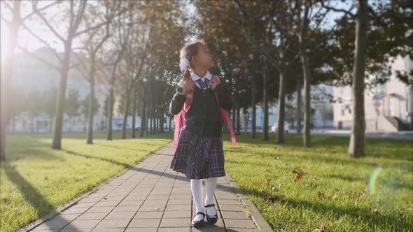Young Girl in School Uniform is Walking in the Park at Sunny Weather Steadicam