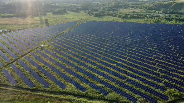 Aerial view of Solar Panels Stand At Sunrise. Flyover Fields Green Energy Landscape alt