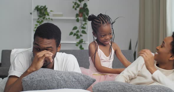 Afro American Family Little Funny Daughter Child Girl Kid Tickles Playing with Mom Lying on Couch alt