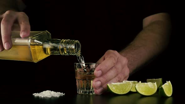 The Barman Holds a Shot and Pours Tequila