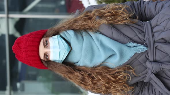 Vertical Shot of Portrait of Caucasian Young Curly Female in Medical Face Mask Standing on Street 