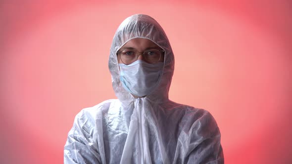 Man in Protective Suit, Medical Mask, Goggles with Arms Crossed on Red Background. Coronavirus Covid
