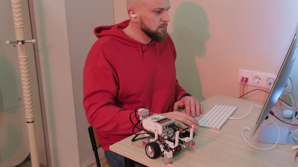Close Up of an Young Bearded Man That is Learning Robotics Lessons Using Computer alt