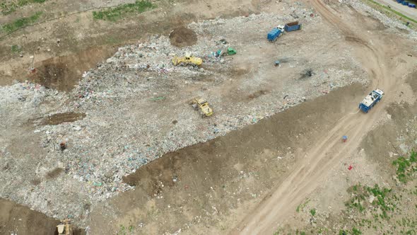 Top View on Garbage Trucks Unload Garbage to a Landfill alt