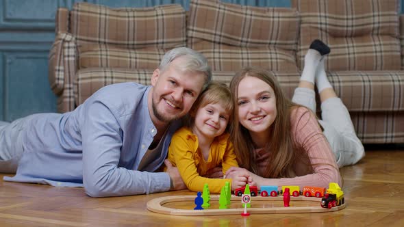 Family of Mother Father with Daughter Child Girl Riding Toy Train on Wooden Railway at Home Room alt