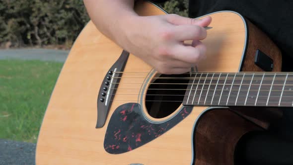 Close Up of a Young Man Playing Acoustic Guitar Outside alt