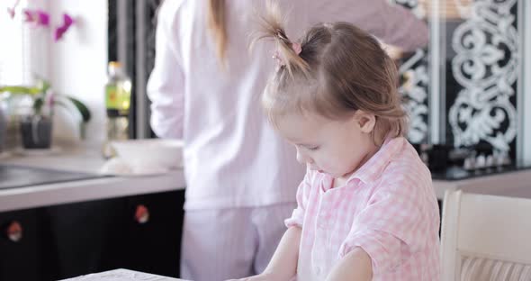 Little Girl Cooking with Caring Mother at Kitchen