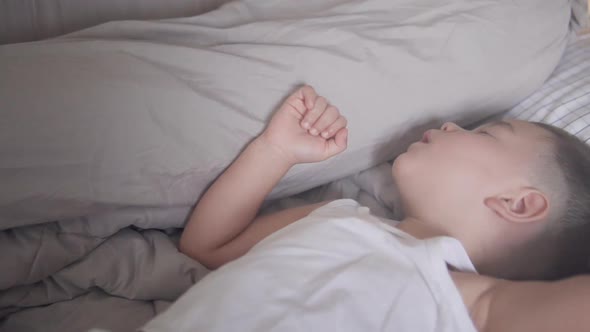 Slow motion truck or slide shot of a sweet two years old Asian boy wearing summer clothes sleeping t alt