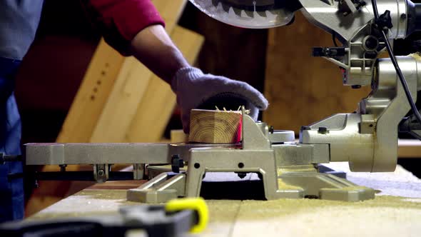Male Carpenter Cuts Off the End of Wooden Beam Using Circular Saw with Laser alt