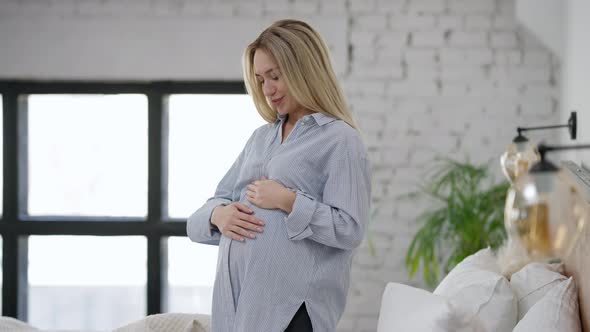 Side View of Happy Pregnant Woman Talking to Unborn Fetus Caressing Belly alt