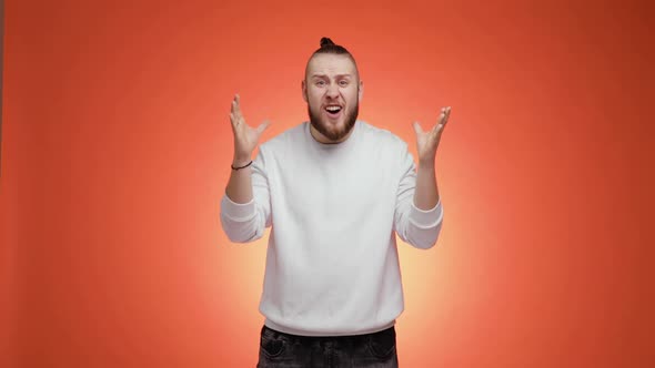 Surprised Bearded Young Man with Hair Tail Says What the Fuck on Red Background