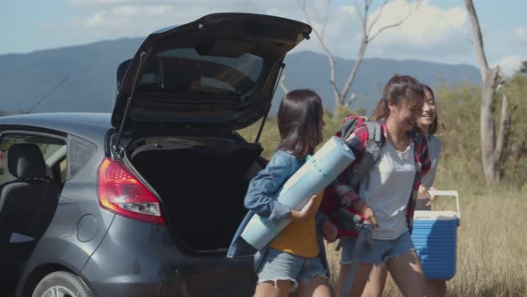 Group of a young teen Asian women helps to hold backpacks and ice coolers with friends camping.