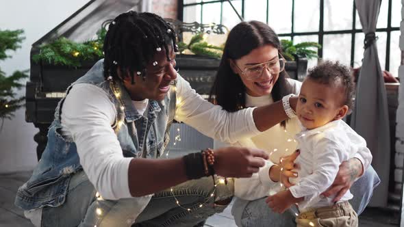 Multiracial Couple Showing Their Baby Boy Son Christmas Lights for the First Time in His Life alt