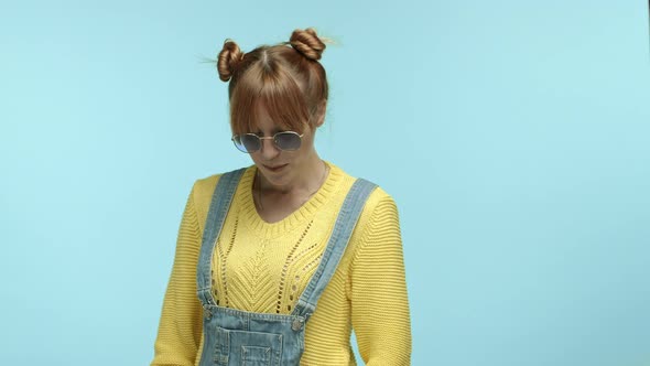 Stylish Young Woman with Buns and Bangs Haircut Wearing Sunglasses Looking Shy and Flushed Glancing