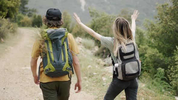 A Happy Couple Backpackers Walking By Forest's Path Rear View alt