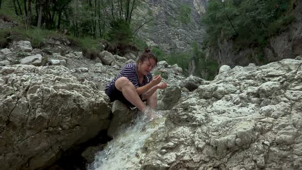 Hiker woman in a rocky valley with spring stream water in the mountain river alt