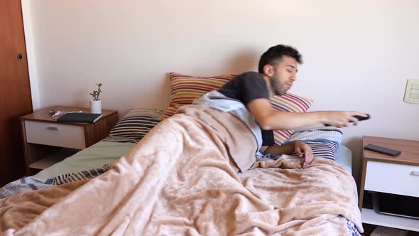 Guy Alone On His Bed Picks Remote Control On Side Table And Turns On Television. - static alt